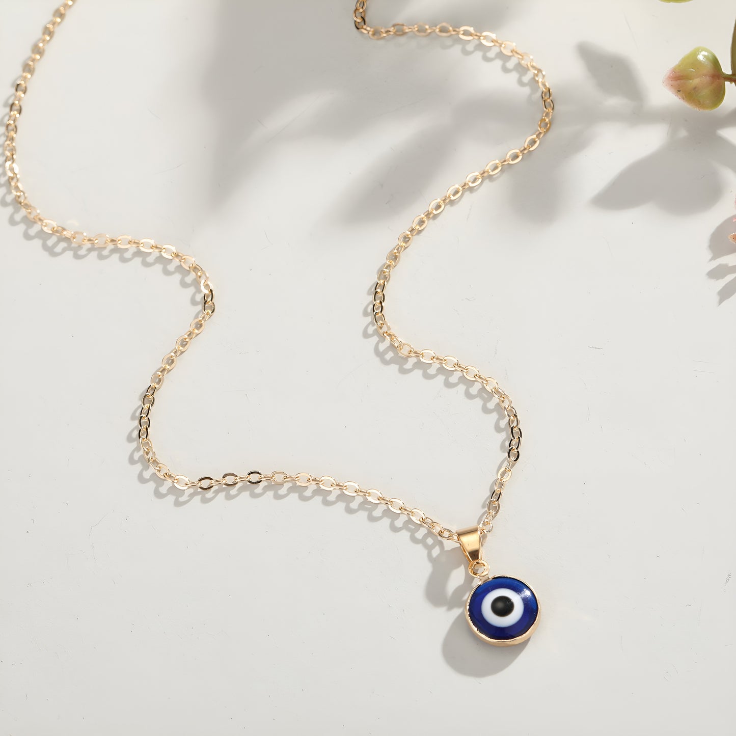 A collection of blue evil eye pendant necklaces with gold-tone chains, displayed in a row on a flat surface.