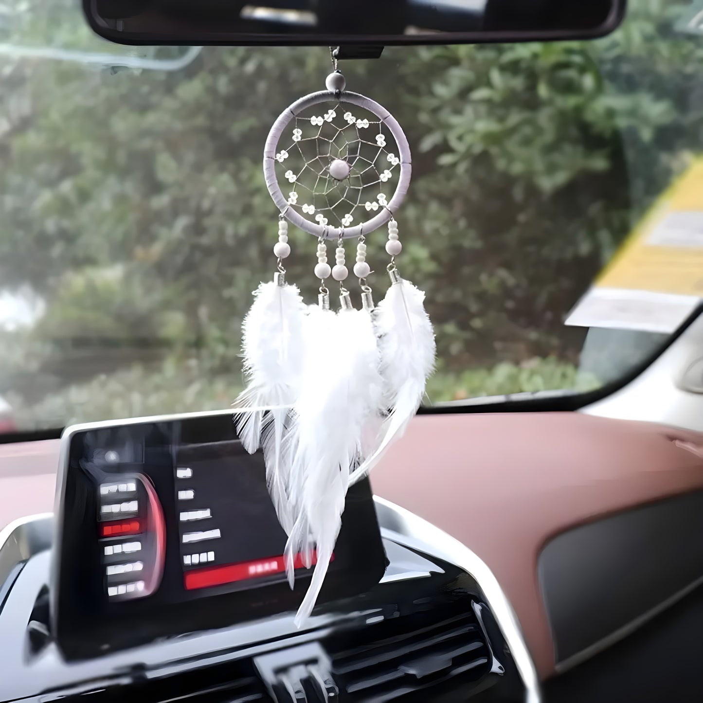 A blue dream catcher hanging from a car mirror with intricate patterns, featuring beads and feathers.