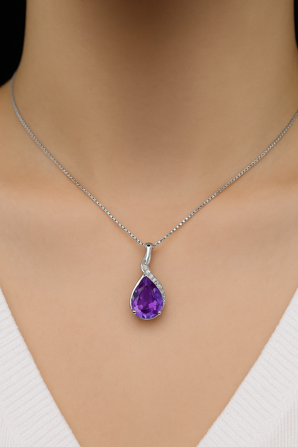 Silver necklace with a purple teardrop pendant on a mannequin
