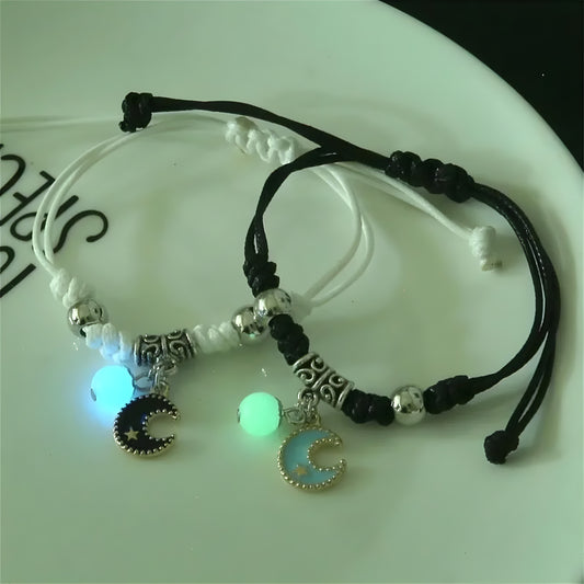 Two couple bracelets with luminous beads. One has a star-shaped bead, and the other has a moon-shaped bead, both with silver accents and black strings.