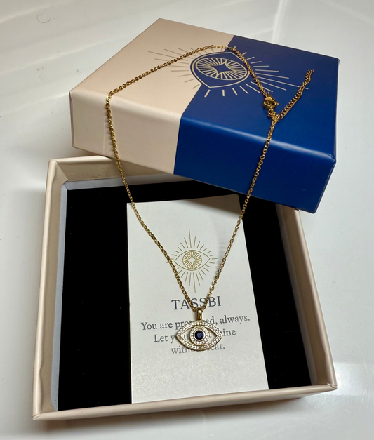 Gold necklace with an eye pendant in a branded box on a white background