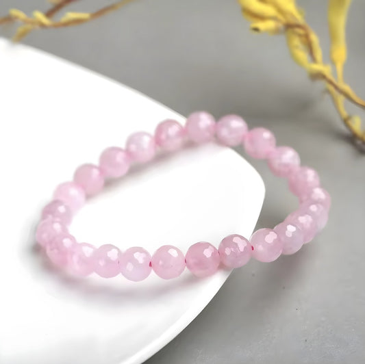 Pink beaded bracelet on a white surface with a blurred background